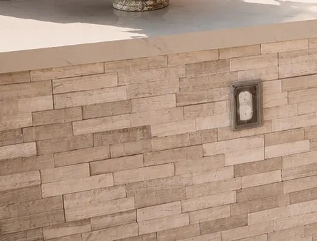 Stacked stone ledger coursing with an outlet cut in cleanly beneath a stone counter overhang.